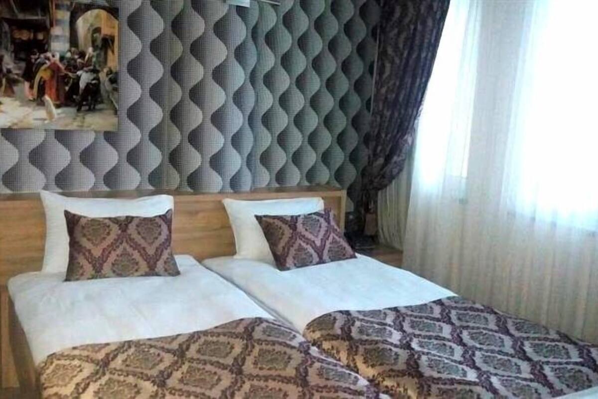 A double bed with patterned bedspreads, a wooden headboard, and a decorative mirror above it.