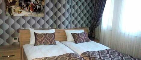 A double bed with patterned bedspreads, a wooden headboard, and a decorative mirror above it.