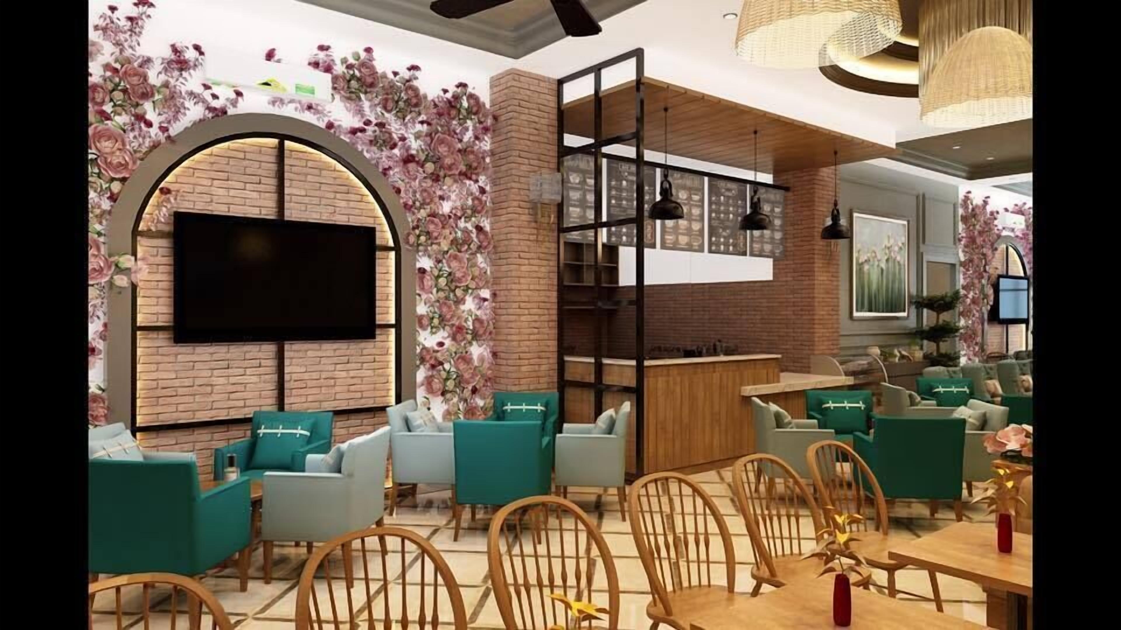 A modern interior with a brick wall, floral wallpaper, and a flat-screen TV. There are green upholstered chairs and a wooden dining table with chairs.