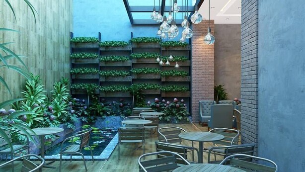 A cozy outdoor seating area with wooden tables and chairs, surrounded by lush greenery and decorative plants. - Prague Hotel Vung Tau (Ho Chi Minh City)