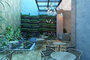 Un espace extérieur accueillant, aménagé avec des tables et des chaises en bois, entouré d’une végétation luxuriante et de plantes décoratives.
