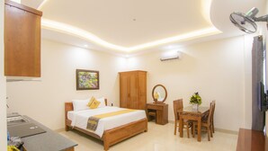 A hotel room with a bed, a desk, a chair, a wooden wardrobe, a mirror, and a painting on the wall. - Prague Hotel Vung Tau (Ho Chi Minh City)