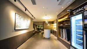 A hotel corridor with a modern design, featuring a large artwork on the left, a clothing rack on the right, and a vending machine. - MIJU HOUSE Gubei-a small white building beside Shanghai oil painting sculpture institute (Shanghai)