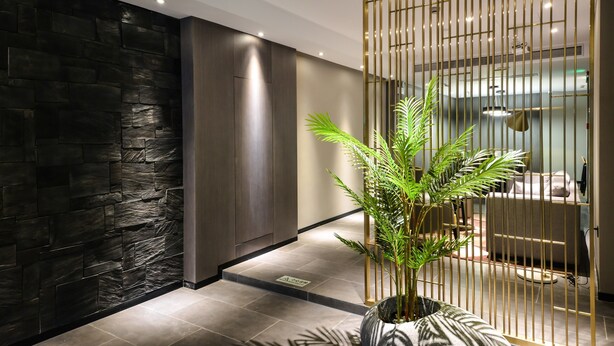 A modern hotel lobby with a stone wall, a wooden panel, a potted plant, and a decorative partition. - MIJU HOUSE Gubei-a small white building beside Shanghai oil painting sculpture institute (Shanghai)