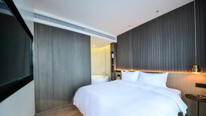 A modern hotel room with a large bed, a bedside table, a wall-mounted TV, and a bathroom with a bathtub. - MIJU HOUSE Gubei-a small white building beside Shanghai oil painting sculpture institute (Shanghai)