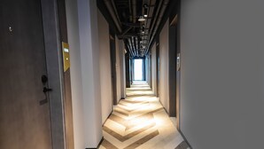 A hallway with a chevron-patterned floor, exposed pipes, and a door with a sign indicating room number 308. - MIJU HOUSE Gubei-a small white building beside Shanghai oil painting sculpture institute (Shanghai)
