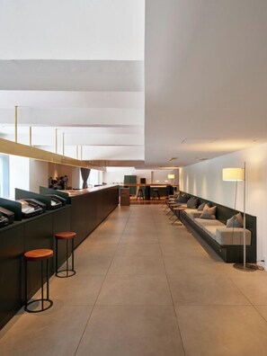 A modern hotel lobby with a long reception desk, seating area, and a high ceiling. - DDD Hotel (Tokyo)