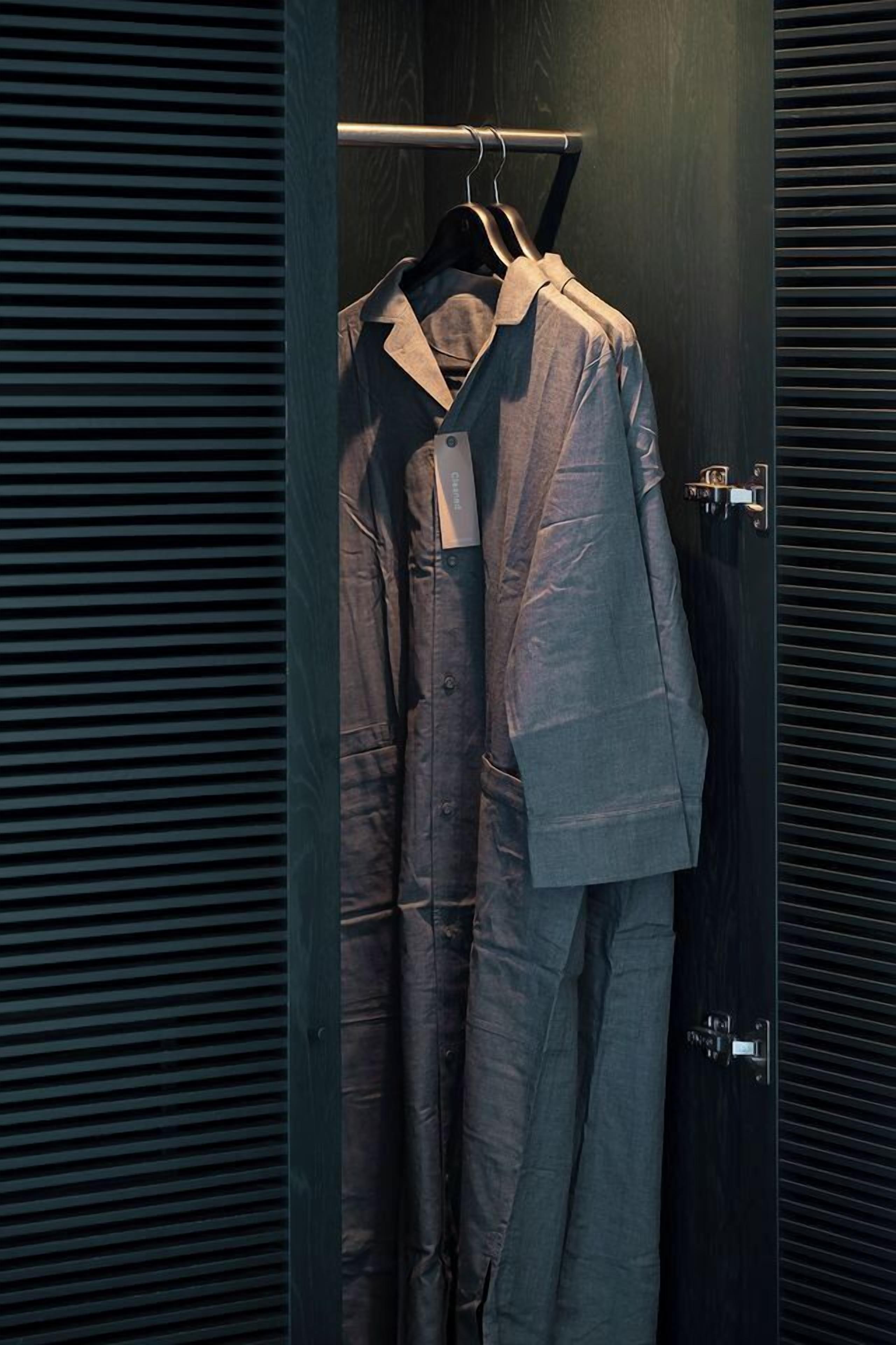 A clothing rack with a suit hanging in a dark room.