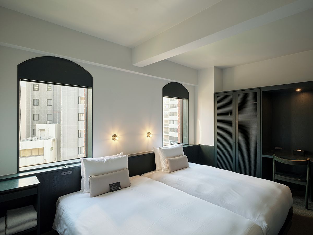 A hotel room with two beds, a desk, and a TV.