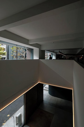 A modern interior with a staircase, a glass wall, and a view of the outside. - DDD Hotel (Tokyo)
