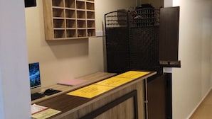 A reception desk with a wooden finish, a clock, and a security camera on the wall. - The Pines Hotel (Kampung Raja)