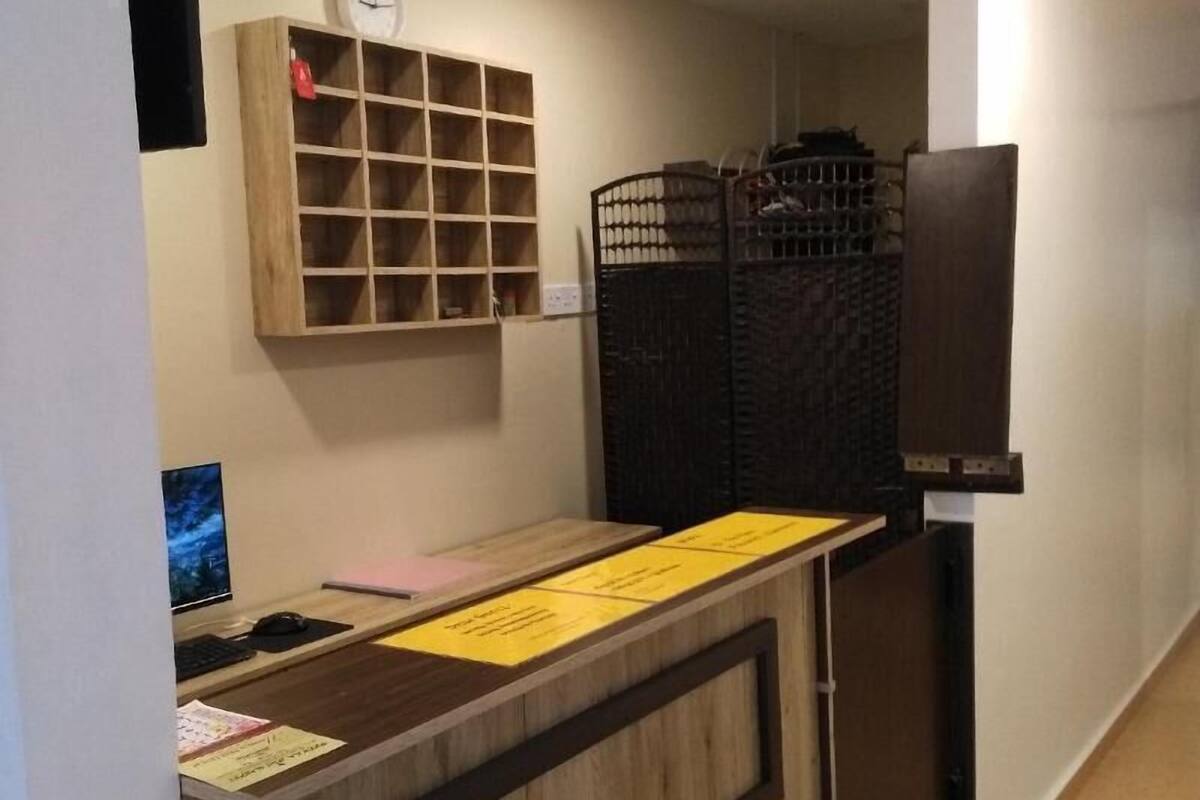 Un comptoir d’accueil avec un écran d’ordinateur, une horloge et un tableau d’affichage.