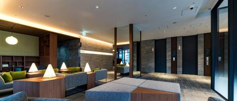 A modern lobby with seating areas, a reception desk, and a large window providing a view.