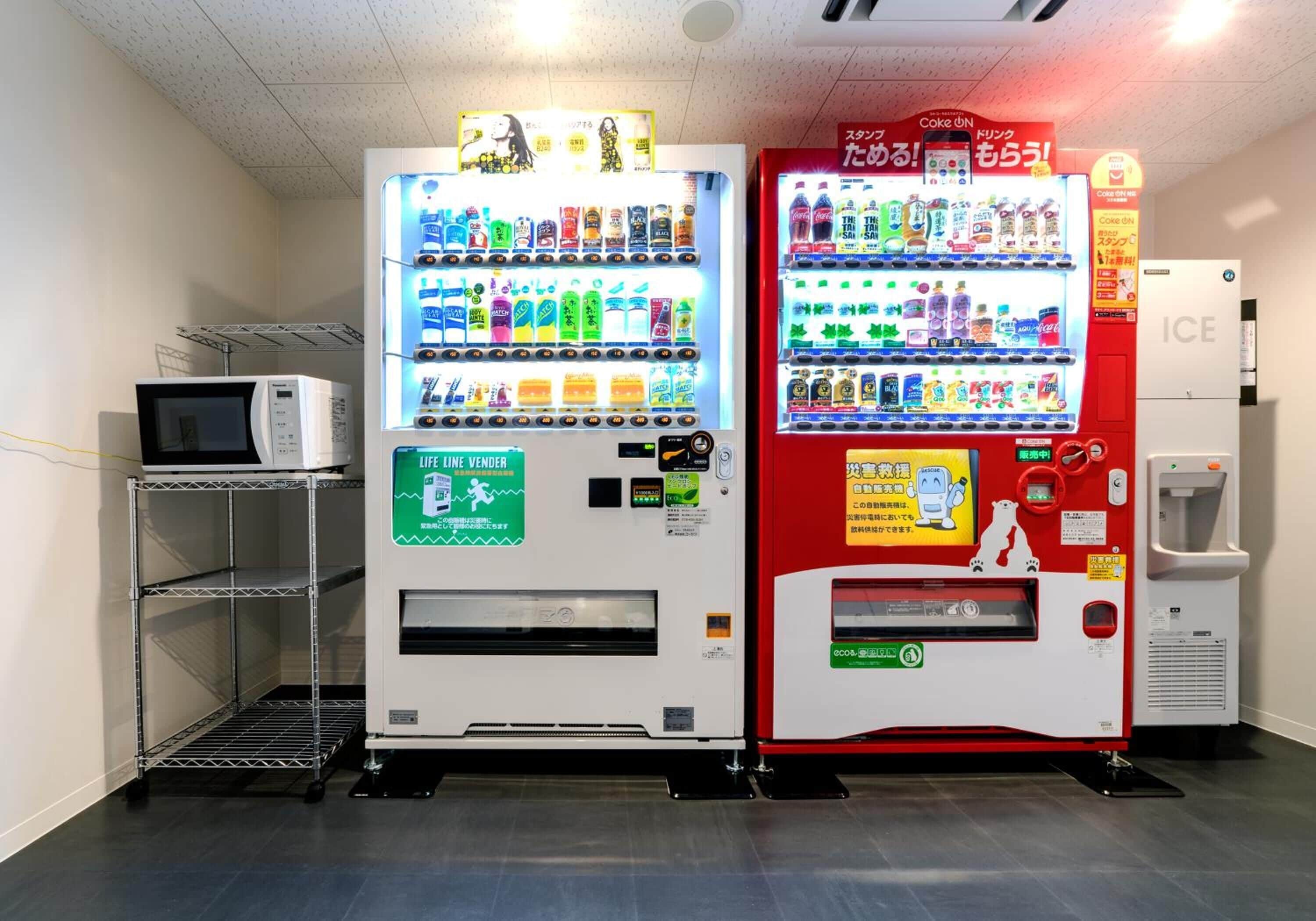Twee automaten, met een magnetron en een waterdispenser op de achtergrond.