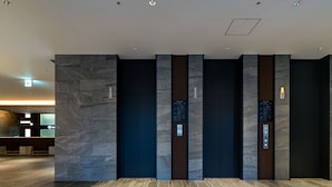 Eine moderne Hotelhalle mit einer Rezeption, einem Grundrissplan und mehreren Aufzügen.
