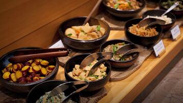 A buffet with various dishes, including fruits, vegetables, and different types of salads.