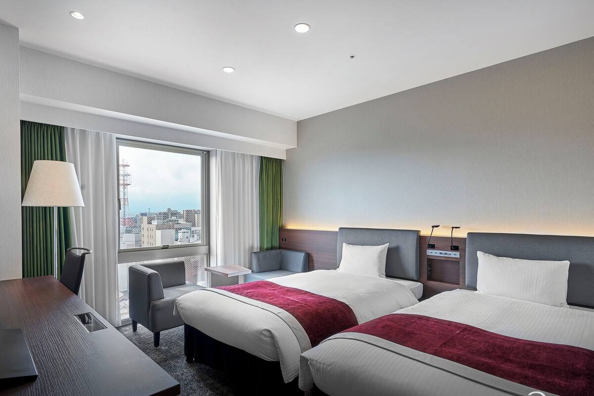 Ein Hotelzimmer mit zwei Betten, einem Schreibtisch und einem Stuhl.