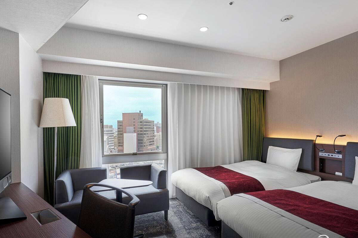 Ein Hotelzimmer mit zwei Betten, einem Schreibtisch und einem Stuhl.