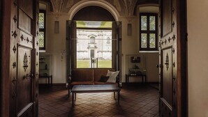 A room with a bench, a large window, and a view of a building outside. - Hotel Monte Pacis (Kaunas)