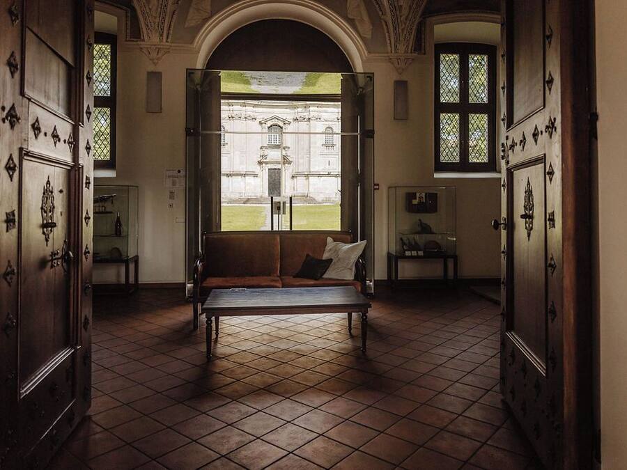 Una habitación con un banco, un ventanal y vista a un edificio.