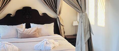 A neatly made bed with a patterned bedspread, a headboard with a crest, and a canopy with curtains.