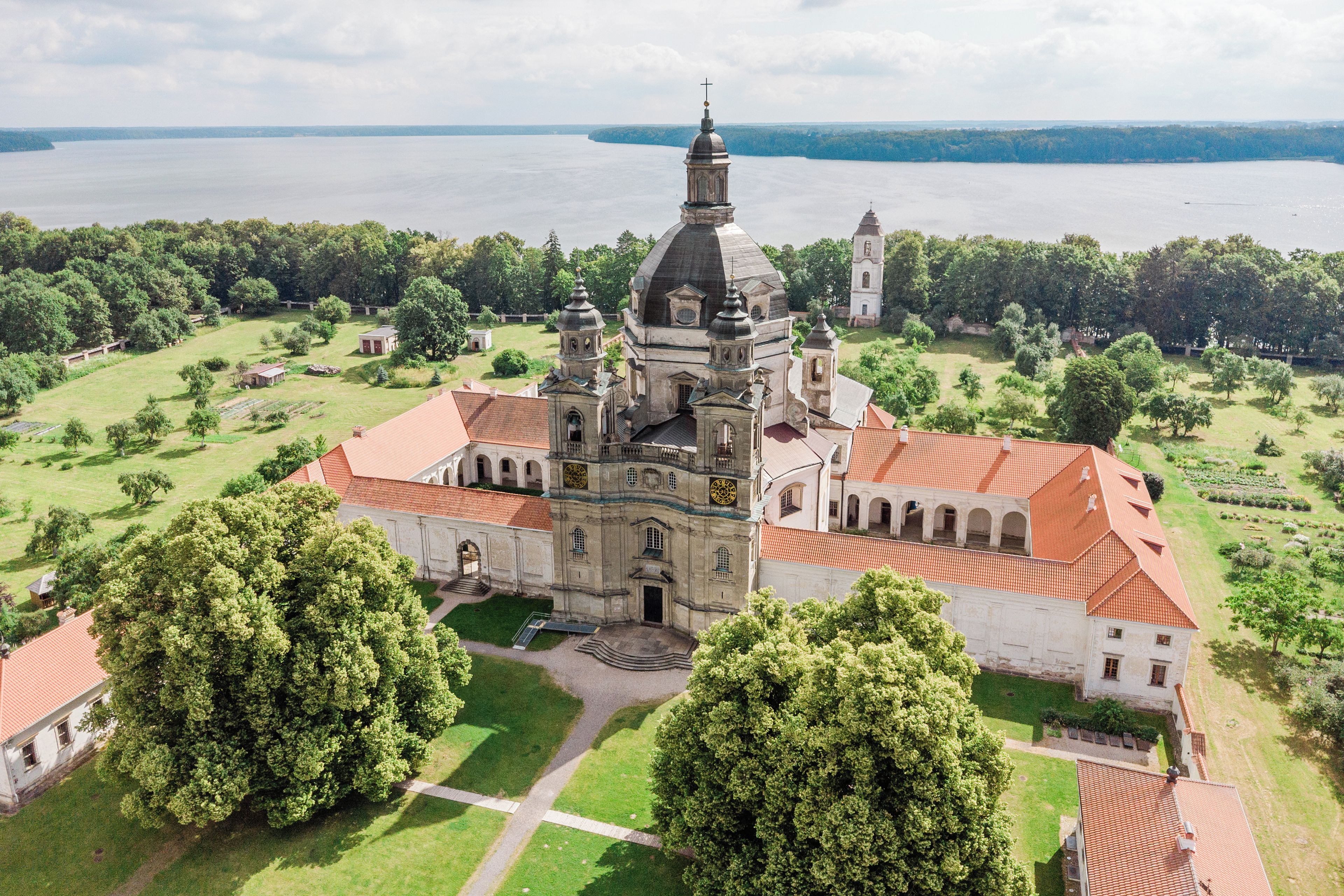 Una iglesia grande con un campanario destacado y un jardín circundante.