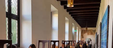 A corridor with tables and chairs, a patterned carpet, and a hanging light fixture.