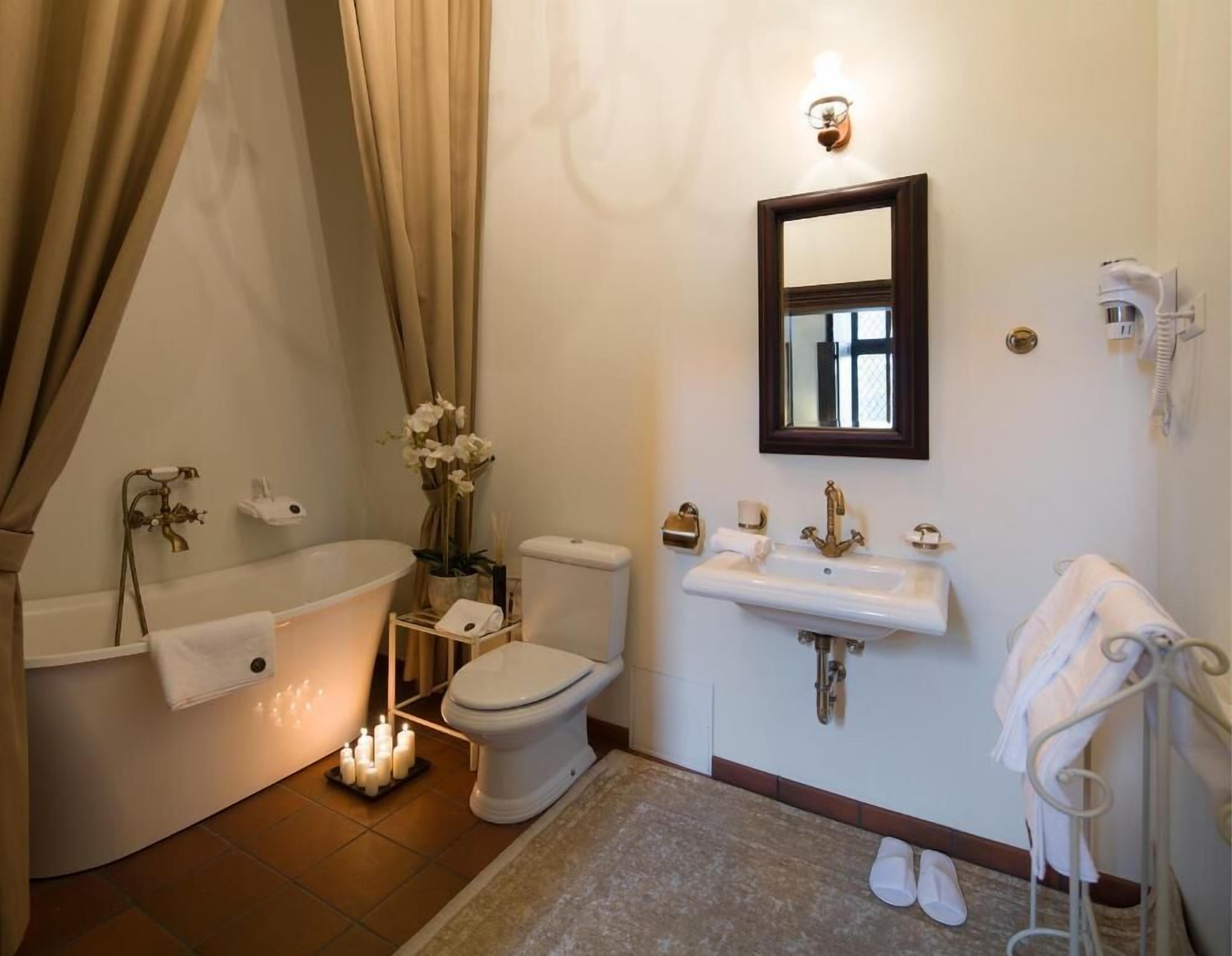 Un baño con bañera, inodoro, lavamanos y espejo.