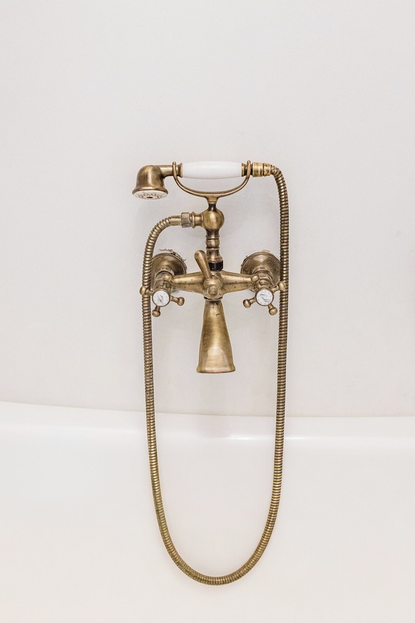 Accesorios de baño de latón con cabezal de ducha y dos caños, probablemente para una bañera.