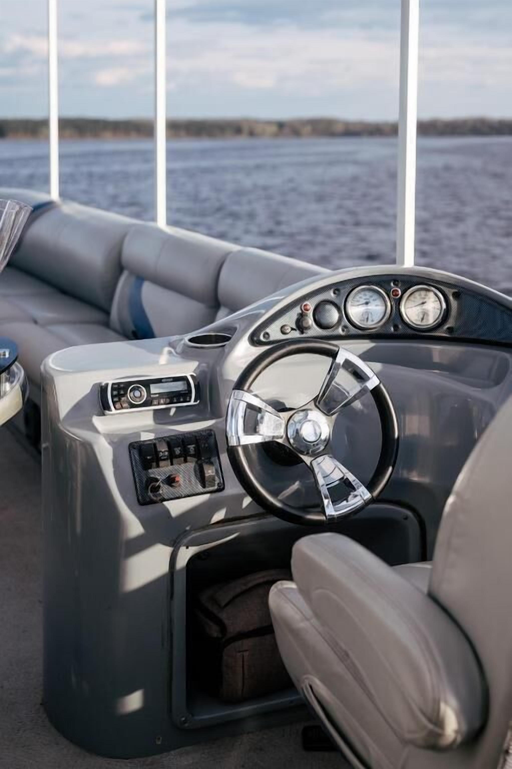 A boat's interior with a steering wheel, control panel, and seating area.