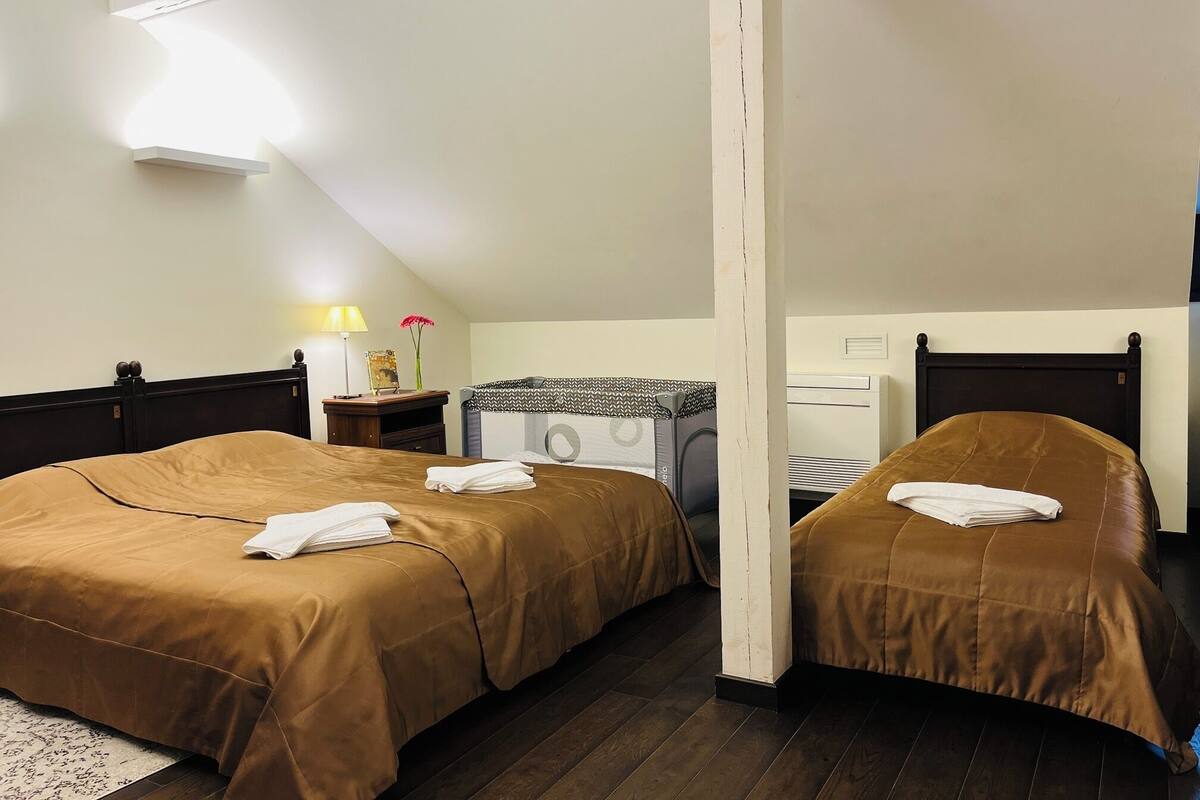 A hotel room with two beds, a washing machine, a lamp, and a small table with a flower.