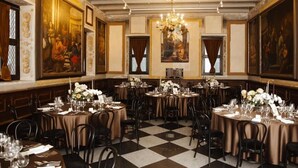 A formal dining room with round tables, black chairs, and floral centerpieces. - Hotel Monte Pacis (Kaunas)