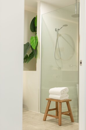 Een aparte badkuip en douche, een diep bad, een regendouche