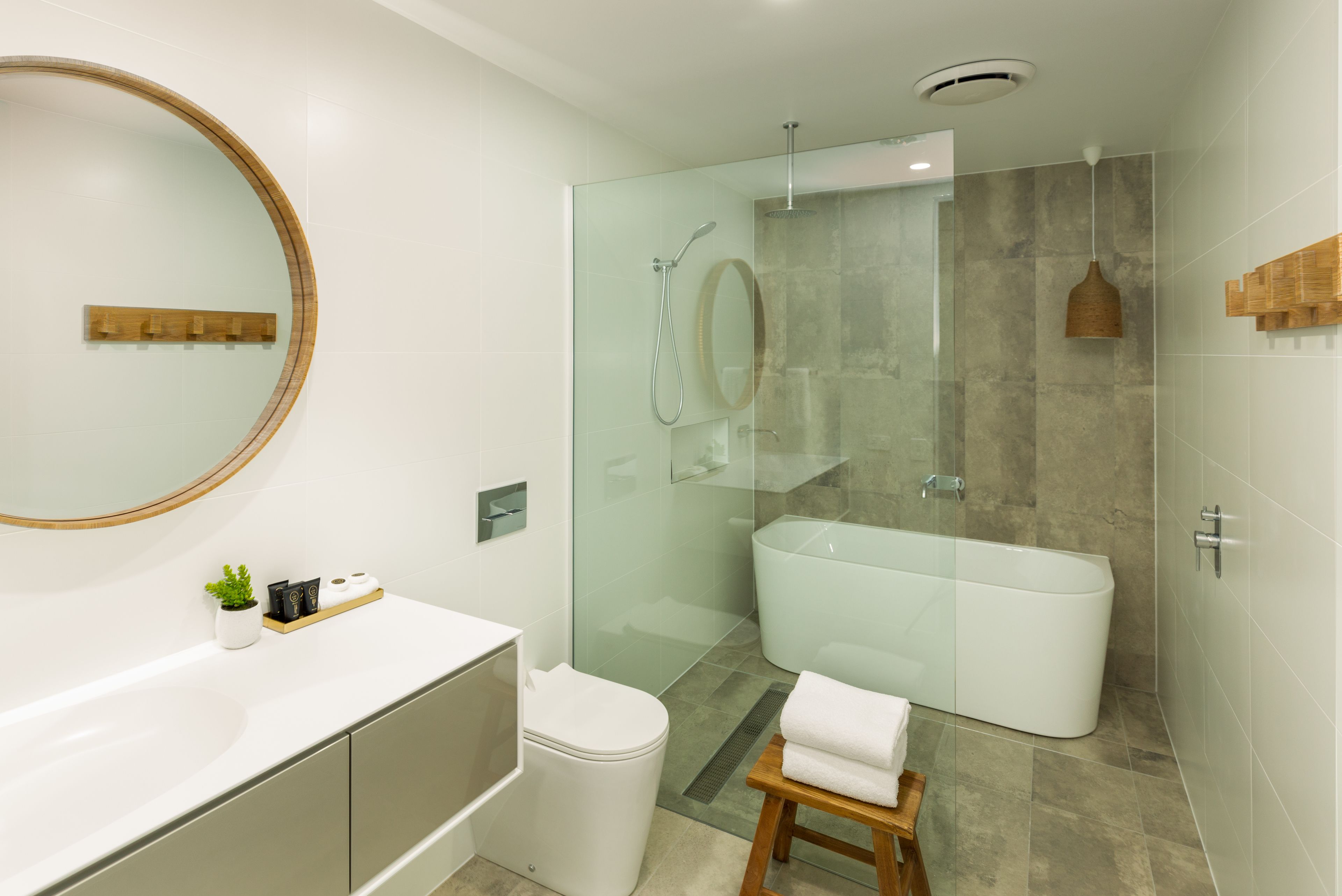 Un baño moderno con ducha de vidrio, bañera independiente y tocador con espejo.