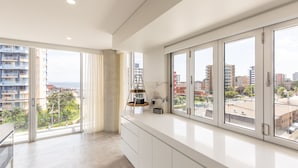 Un appartement moderne doté de grandes fenêtres, d’un balcon et offrant une vue sur le paysage urbain.