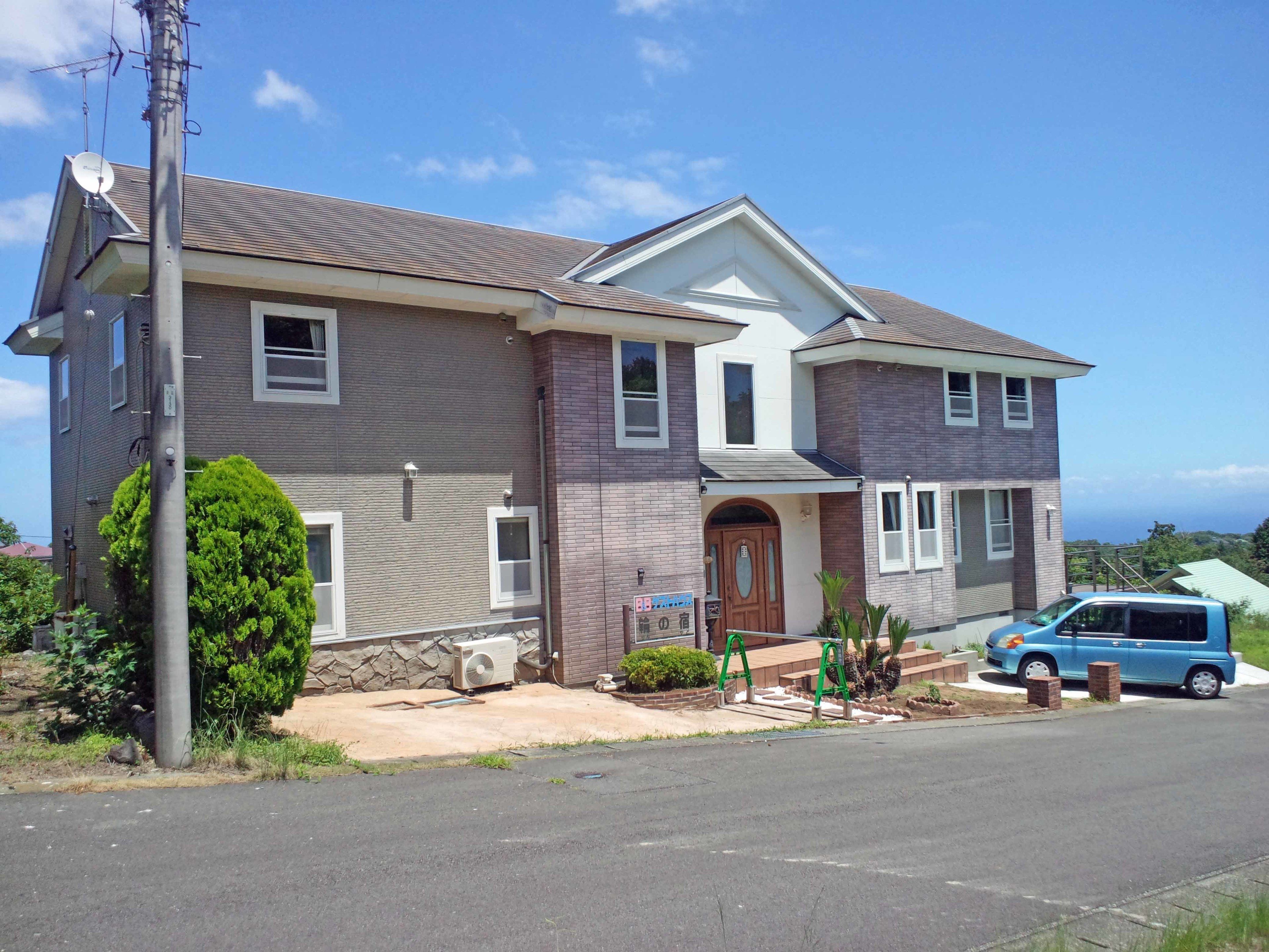 A two-story house with a brick exterior, a front porch, and a satellite dish.