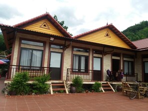 A two-story building with a yellow facade, large windows, and a balcony. - Mai Chau Xanh Bungalow (Mai Chau)