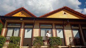 A two-story building with a symmetrical facade, large windows, and a red-tiled roof. - Mai Chau Xanh Bungalow (Mai Ha)