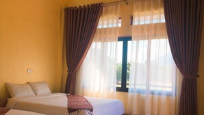 A room with two beds, a window with curtains, and a view of the outdoors. - Mai Chau Xanh Bungalow (Mai Ha)