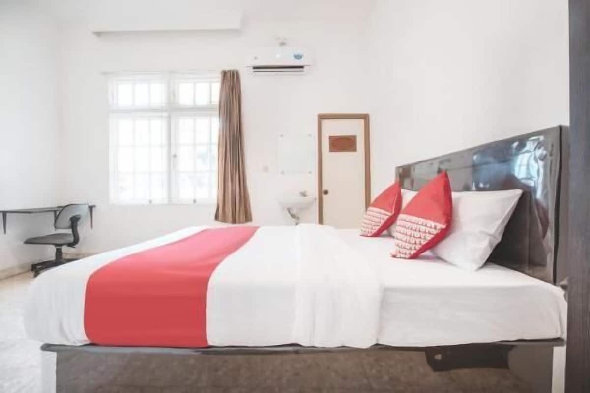Une chambre d’hôtel avec un lit, une fenêtre avec des rideaux, une porte et un appareil de climatisation.