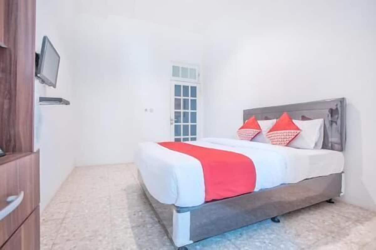 Une chambre à coucher avec un lit, une télévision et une porte.