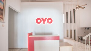 Un comptoir d’accueil avec une enseigne « OYO », un escalier et un tableau accroché au mur.