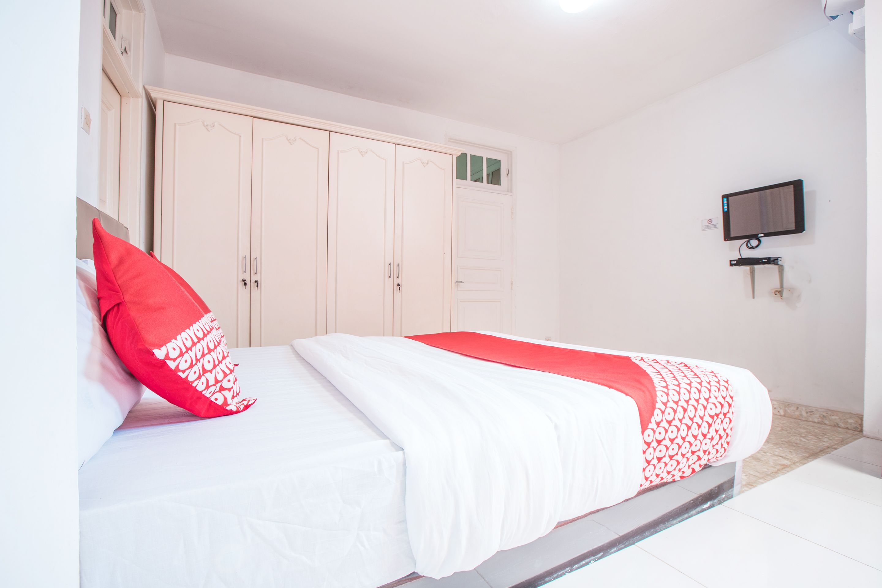 Un dormitorio con una cama, un armario y un televisor en la pared.