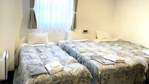 Een hotelkamer met twee bedden, een raam met gordijnen, een thermostaat en een radiator.