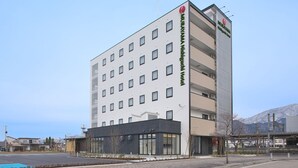 Een modern hotelgebouw met een platte gevel, veel ramen en een opvallend bord met de naam Murayama Nishiguchi Hotel.
