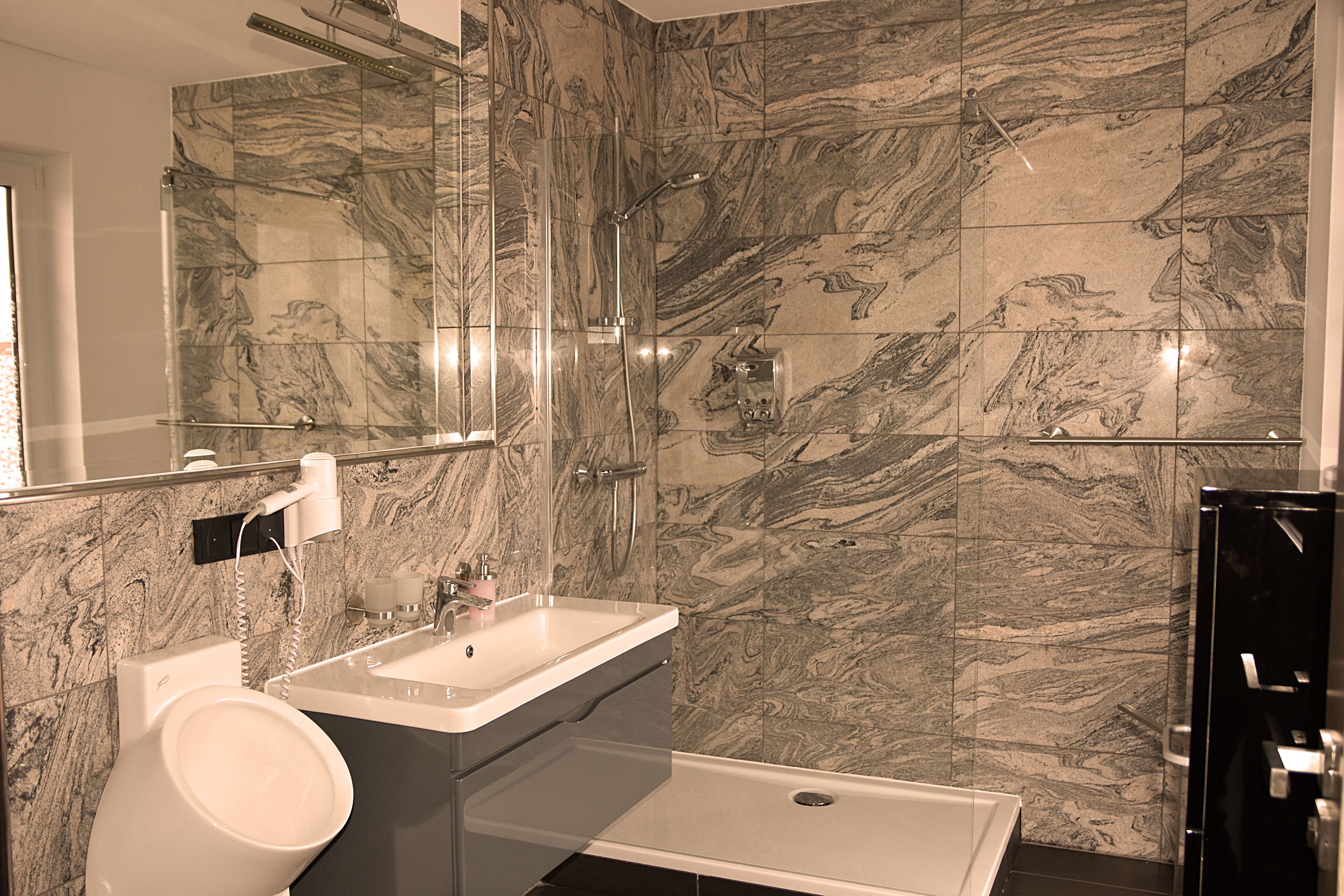 A modern bathroom with a marble backsplash, a white sink, and a black bathtub.