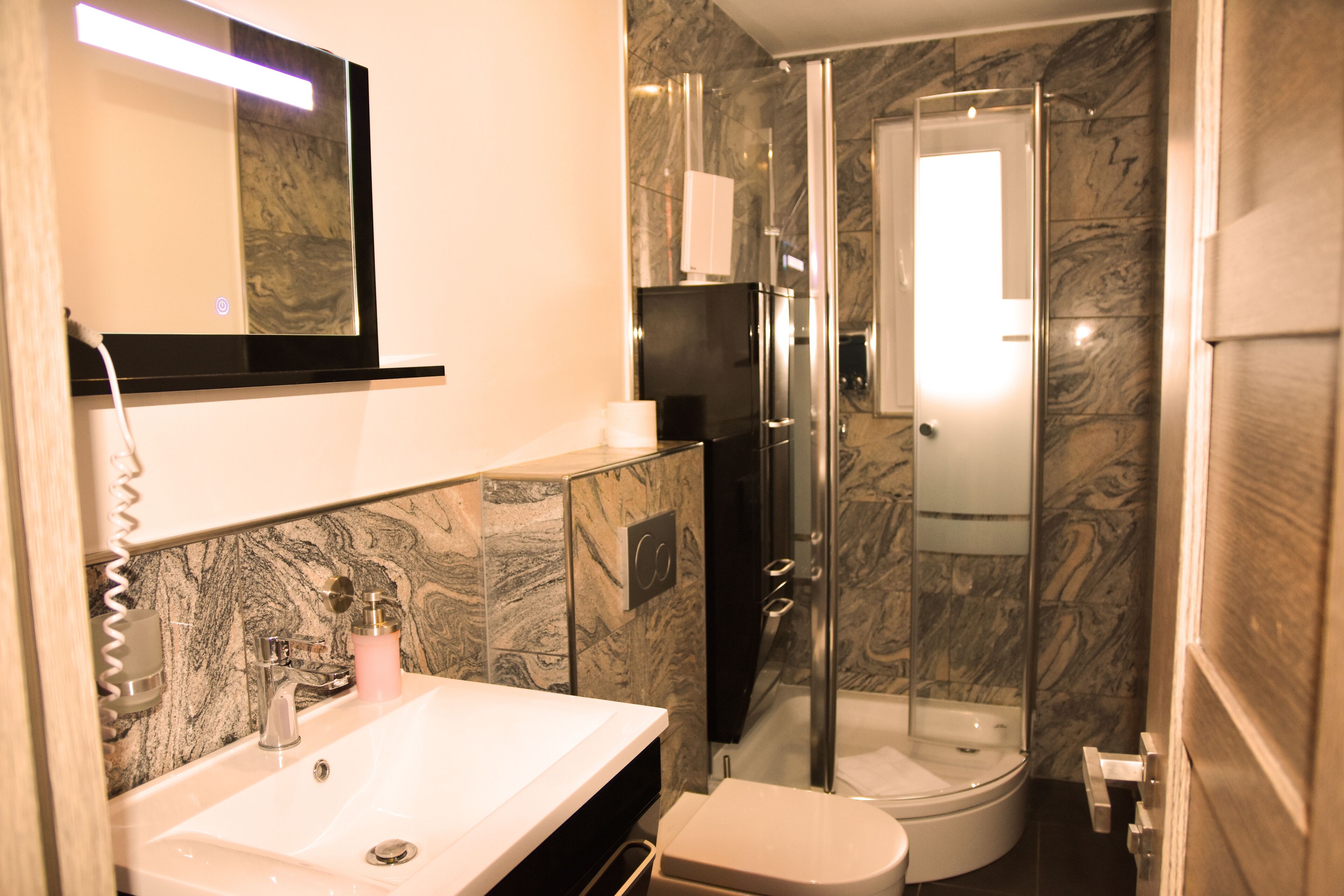 A bathroom with a marble sink, a toilet, and a glass-enclosed shower.