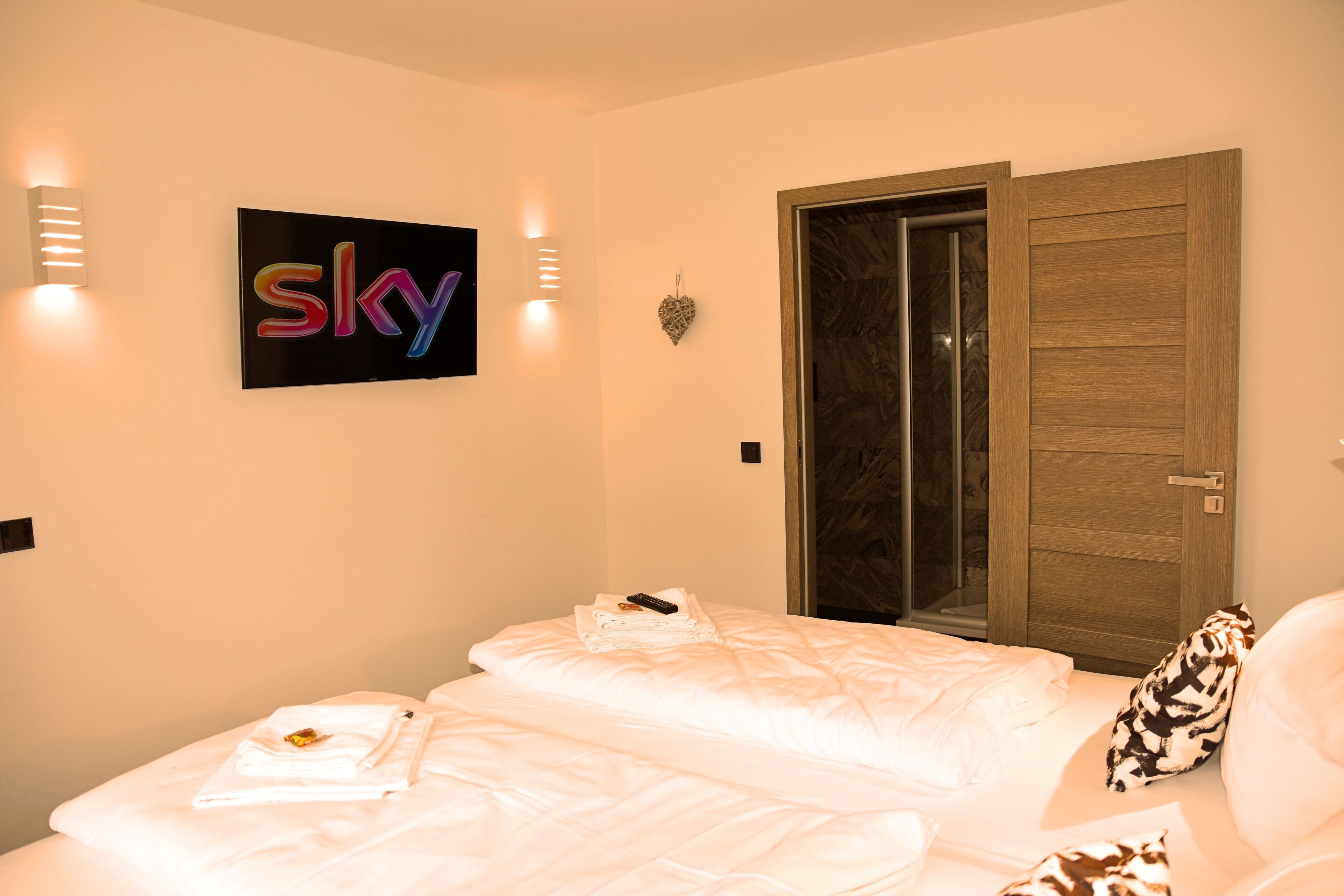 A hotel room with a bed, a wardrobe, and a 'sky' sign on the wall.