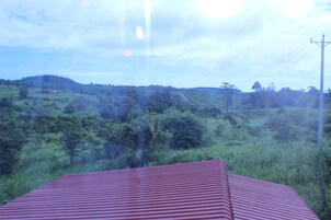 Un edificio con techo rojo y vistas a un paisaje verde y un camino sinuoso.