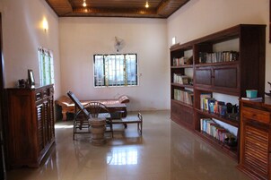 Une pièce spacieuse avec une bibliothèque en bois, une table à manger entourée de chaises et une fenêtre agrémentée d’éléments décoratifs.